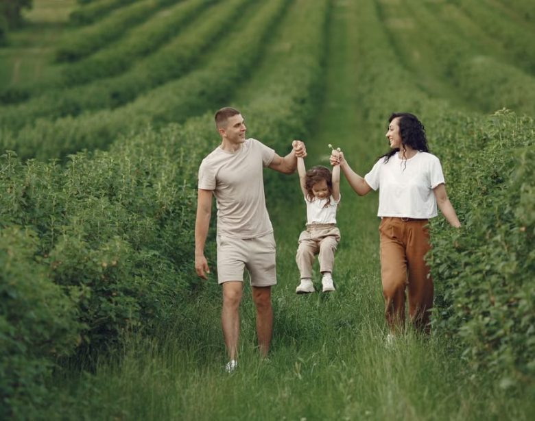 A happy family walking in a lush, green rural field together.